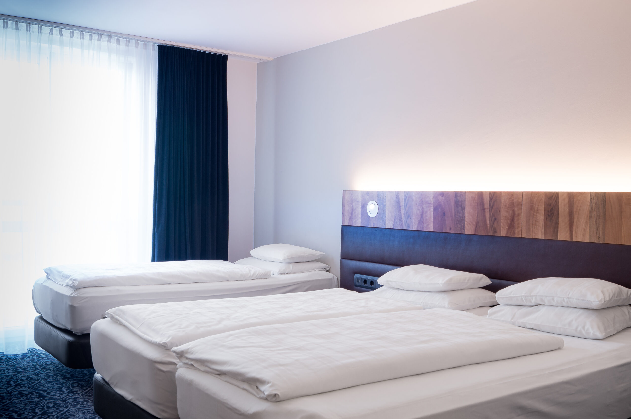 DRZ Moderner Hotelraum mit zwei Einzelbetten im Grauer Bär Innsbruck Hotel, stilvoll eingerichtet, weiche Beleuchtung.